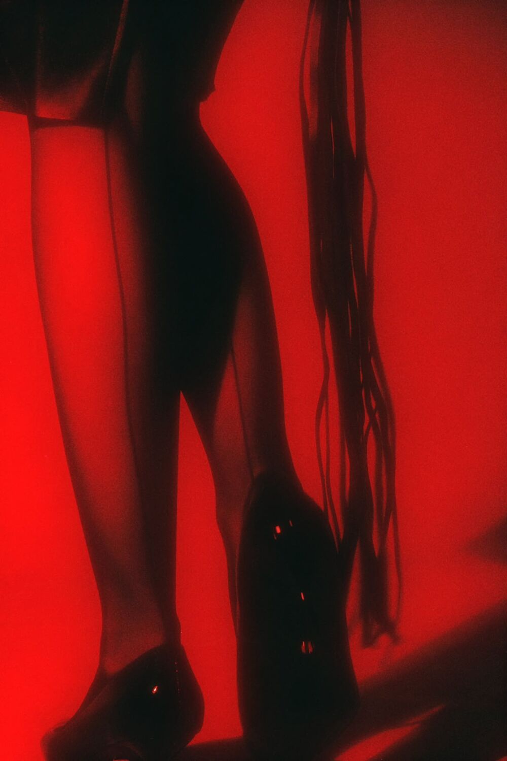 Silhouette in seamed stockings and heels, red light